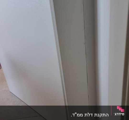 דלת לבנה פתוחה על רצפת אריחים אפורה